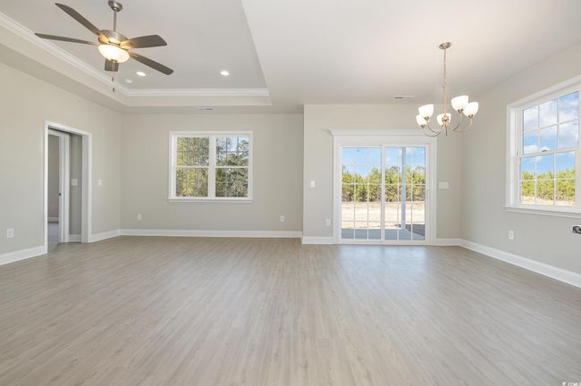Unfurnished room featuring hardwood / wood-style floors, ceiling fan with notable chandelier, ornamental molding, and a tray ceiling | Image 7