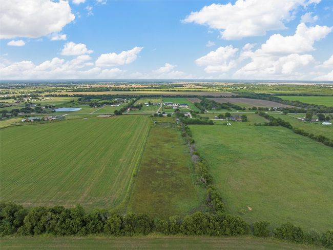 Aerial view of sparsely populated area with large plots for crops and a large body of water | Image 30