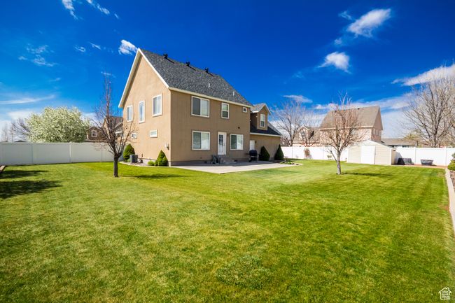 Rear view of property with a patio, a storage unit, an outbuilding, a lawn, and a fenced backyard | Image 37