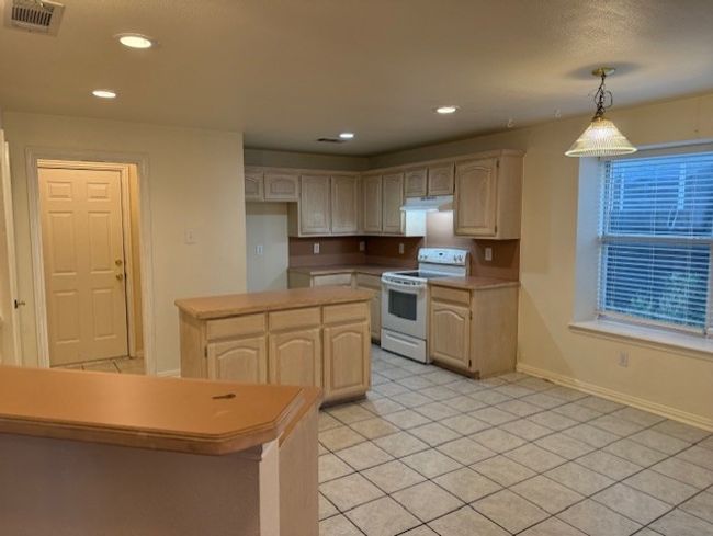Kitchen featuring electric stove, recessed lighting, light countertops, light tile patterned floors, and decorative light fixtures | Image 6