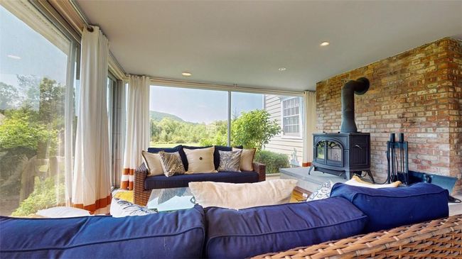 Living room featuring a wood stove and brick wall | Image 13