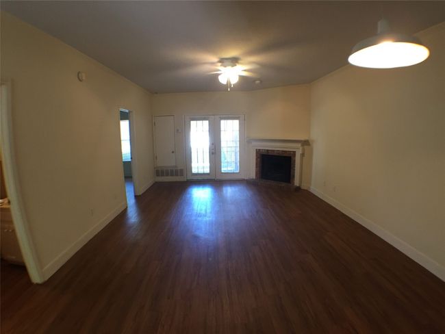 Unfurnished living room featuring radiator heating unit, ceiling fan, baseboards, a fireplace, and dark wood-style flooring | Image 16
