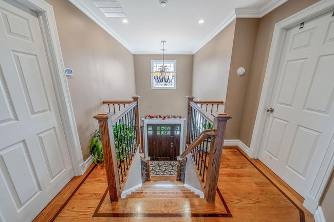 Stairway featuring visible vents, ornamental molding, a notable chandelier, and wood finished floors | Image 14