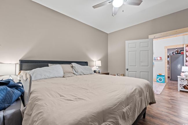 Bedroom featuring lofted ceiling, wood finished floors, freestanding refrigerator, and ceiling fan | Image 33