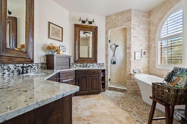 Bathroom featuring a freestanding bath, a stall shower, stone tile floors, decorative backsplash, and vanity | Image 16
