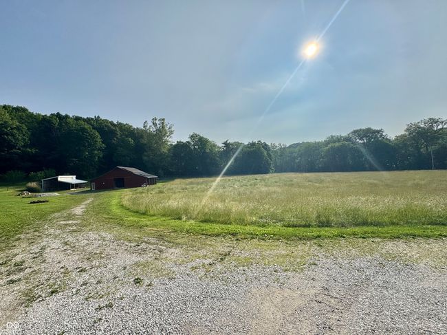view of yard featuring a view of countryside, driveway, an outdoor structure, a forest view, and a pole building | Image 11