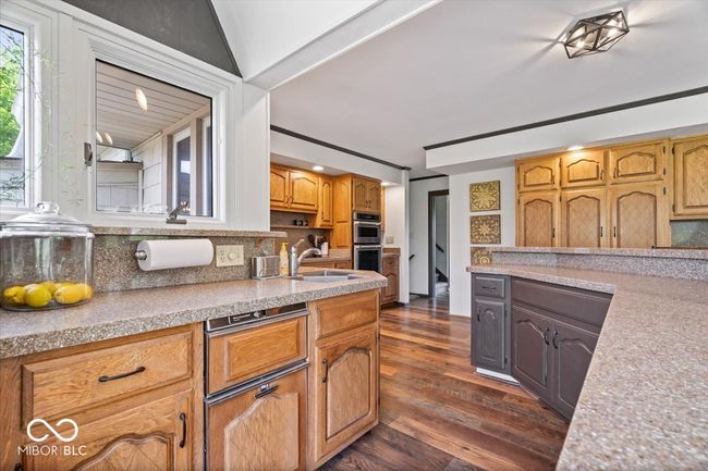kitchen featuring a sink, backsplash, double oven, and dark wood-style flooring | Image 17