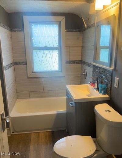 Full bathroom featuring shower / bathtub combination, vanity, hardwood / wood-style flooring, and tasteful backsplash | Image 2