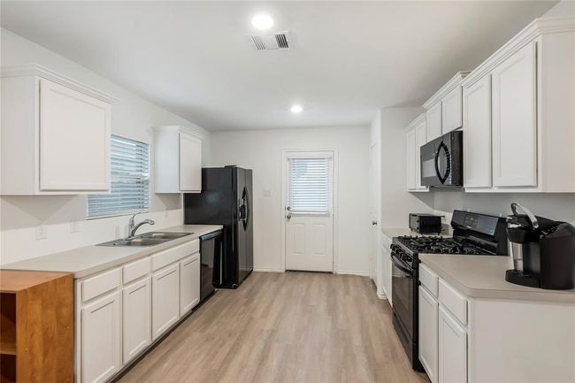 Another view of the kitchen, showcasing the open layout and modern finishes. | Image 9