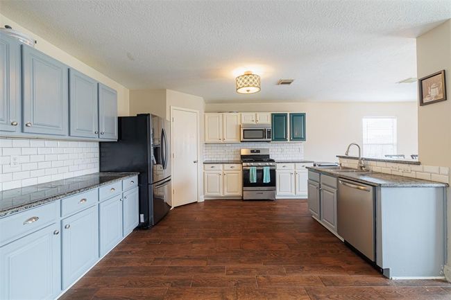 Kitchen features granite counters, lots of cabinets and tile backsplash. | Image 6