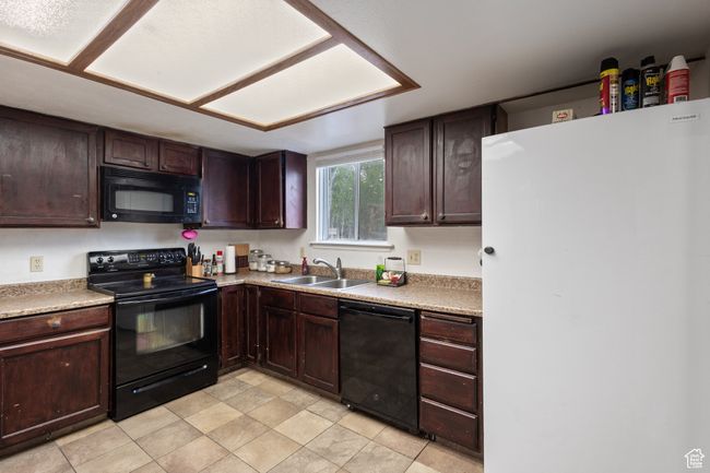 Kitchen featuring black appliances, light countertops, and dark brown cabinetry | Image 6