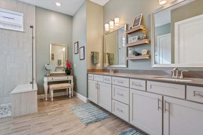 Full bathroom featuring double vanity, a make up area, a walk in shower, & wood look tile flooring | Image 20