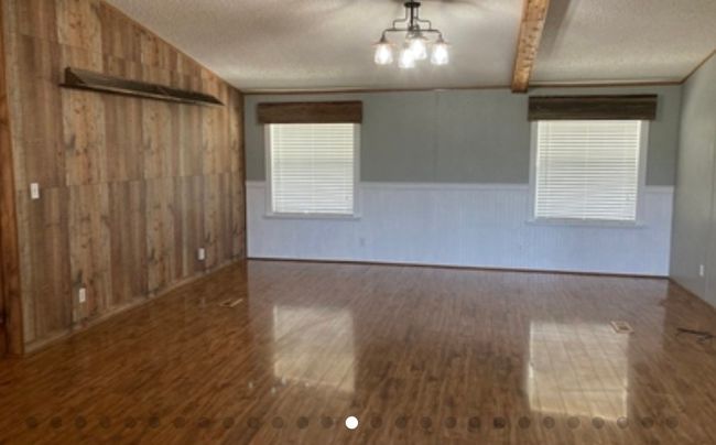 Empty room featuring wooden walls, a wainscoted wall, wood finished floors, and a textured ceiling | Image 19