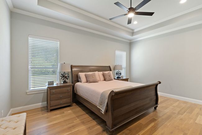 Bedroom with light wood-style flooring, a raised ceiling, baseboards, recessed lighting, and ornamental molding | Image 15