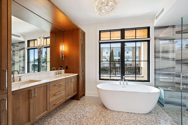 Spa-like primary bath with heated floors, dual vanity areas, large soaker tub, and curbless walk-in shower | Image 19