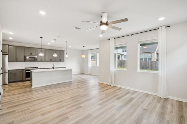 Kitchen featuring stainless steel appliances, gray cabinets, a sink, open floor plan, and recessed lighting | Image 5