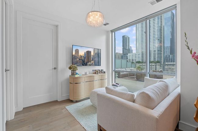 Living room featuring light wood-style floors, a wall of windows, and a chandelier | Image 11