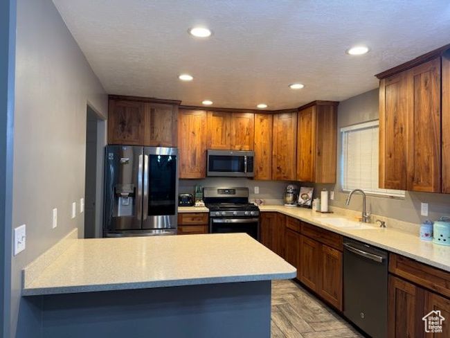Kitchen with stainless steel appliances, a sink, light countertops, and recessed lighting | Image 17