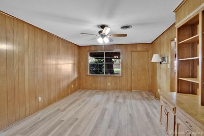 Empty room featuring light hardwood / wood-style floors, wood walls, and ceiling fan | Image 2