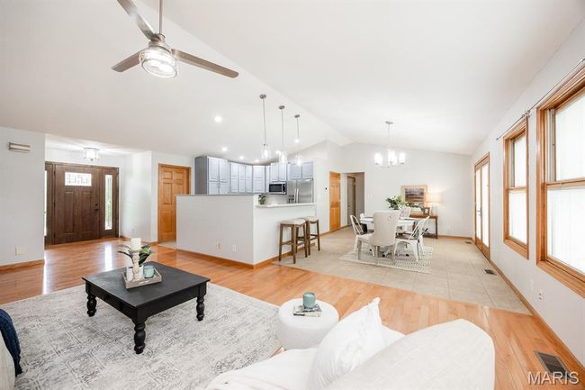 Living area with vaulted ceiling, a chandelier, light wood finished floors, and ceiling fan | Image 13