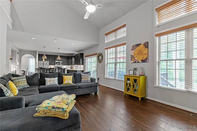 Living area featuring dark wood-style floors, stairs, a high end fireplace, and a high ceiling | Image 17