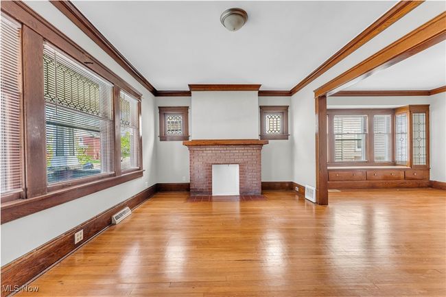 Unfurnished living room featuring a wealth of natural light, visible vents, crown molding, and light wood-style flooring | Image 4