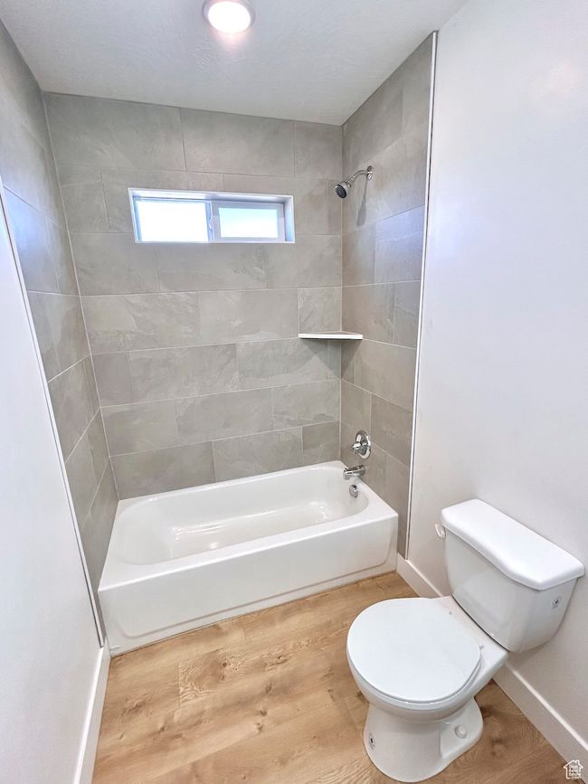Full bathroom featuring baseboards, wood finished floors, toilet, and shower / washtub combination | Image 15