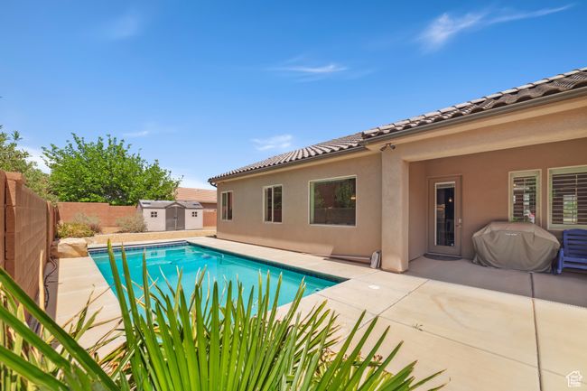 View of swimming pool featuring a storage unit, a fenced in pool, an outbuilding, a fenced backyard, and a patio area | Image 5