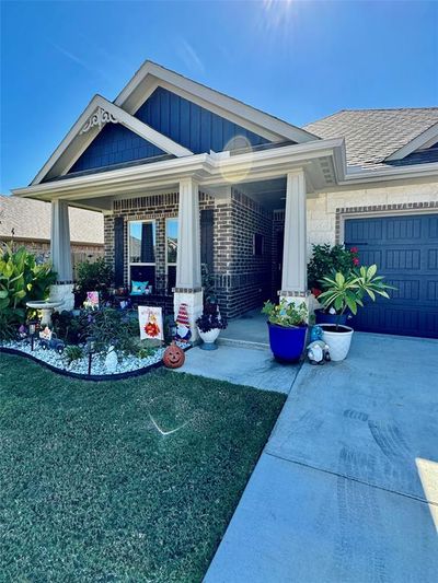 Entrance to property featuring covered porch, a yard, and a garage | Image 2