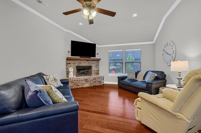 Living room with ornamental molding, visible vents, vaulted ceiling, and wood finished floors | Image 8