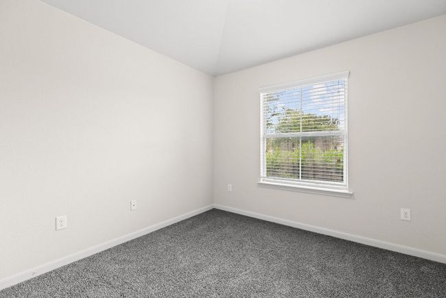 Empty room with dark carpet, baseboards, and vaulted ceiling | Image 4