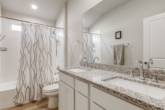 Bathroom with shower / tub combo, double vanity, toilet, and wood finished floors | Image 25