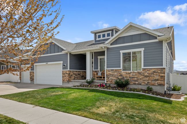 Craftsman-style house with board and batten siding, stone siding, a shingled roof, an attached garage, and a front lawn | Image 23