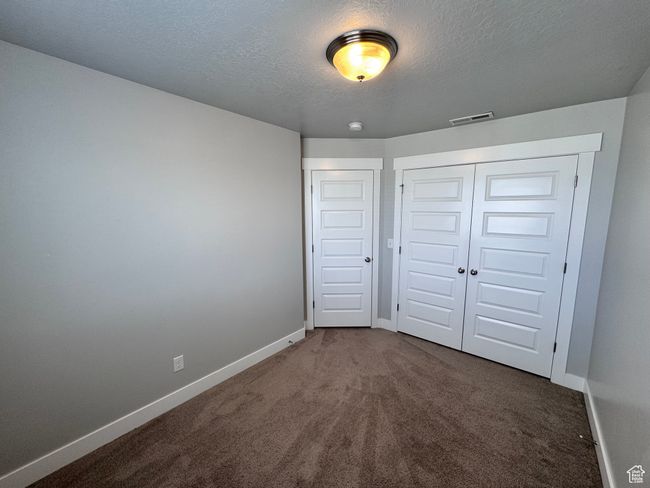 Unfurnished bedroom with a textured ceiling, visible vents, carpet flooring, and baseboards | Image 18