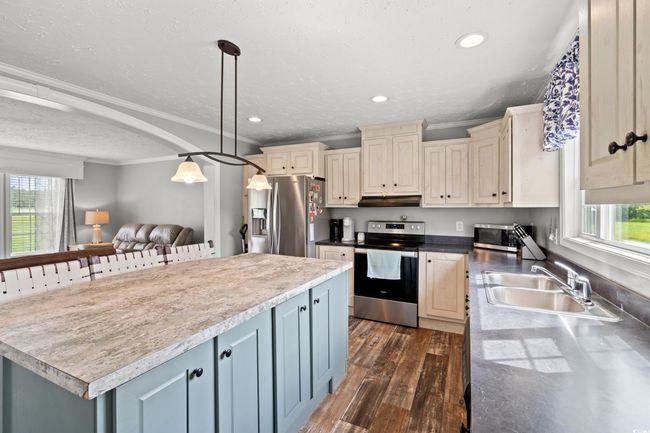 Kitchen with stainless steel appliances, crown molding, under cabinet range hood, plenty of natural light, and cream cabinetry | Image 7