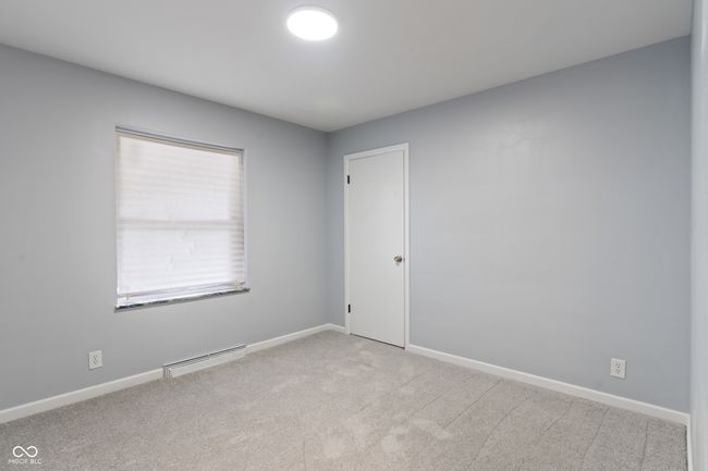 unfurnished room with light carpet, baseboards, and a baseboard heating unit | Image 26