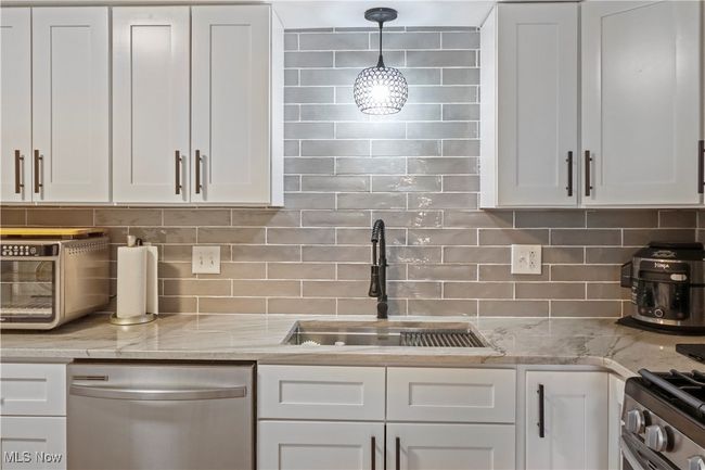 Kitchen with white cabinetry, tasteful backsplash, a sink, stainless steel appliances, and a toaster | Image 4