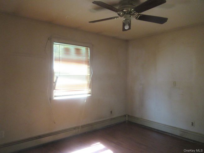 Unfurnished room with a ceiling fan, wood finished floors, and baseboard heating | Image 9