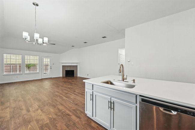 Kitchen with dishwasher, a sink, a chandelier, a fireplace, and light countertops | Image 15
