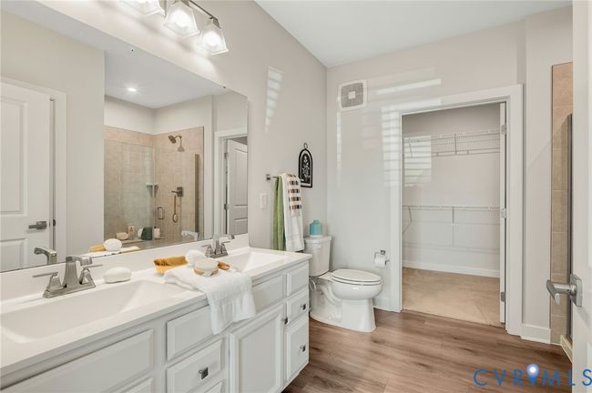 Bathroom with wood finished floors, double vanity, tiled shower, and a spacious closet | Image 14