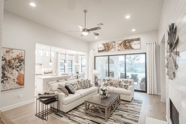 Living room with light wood-type flooring, a ceiling fan, healthy amount of natural light, recessed lighting, and a fireplace | Image 15