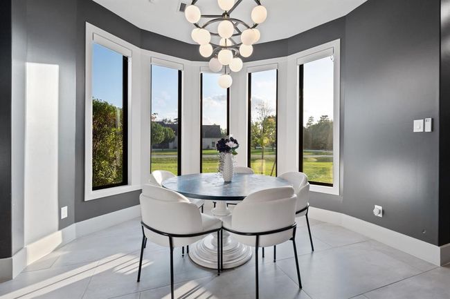 A modern dining area with large windows offering a scenic view. The space is well-lit, with a contemporary chandelier and dark accent walls, creating a stylish and inviting atmosphere. | Image 22