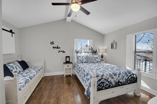 Bedroom with dark wood-style flooring, a ceiling fan, baseboards, and a barn door | Image 9