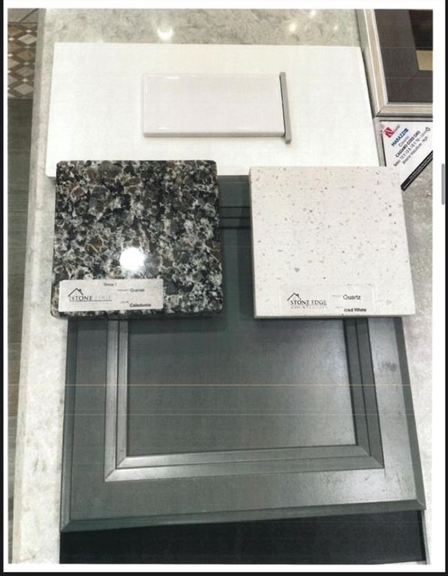 This image shows a selection of home design materials, including a dark gray cabinet door, a granite sample with a mix of black and white, a white quartz sample with subtle gray speckles, and a small white tile. Ideal for visualizing kitchen or bathroom finishes. | Image 34