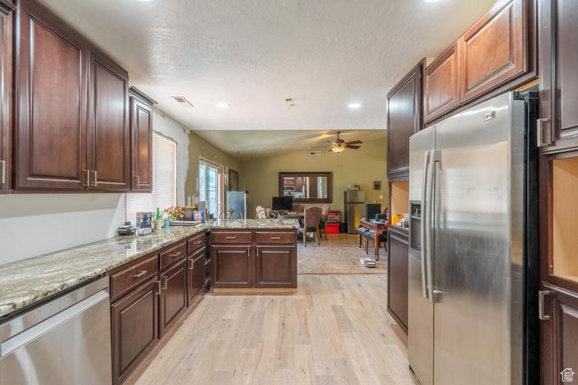 Kitchen featuring stainless steel appliances, a ceiling fan, light wood-type flooring, recessed lighting, and open floor plan | Image 27
