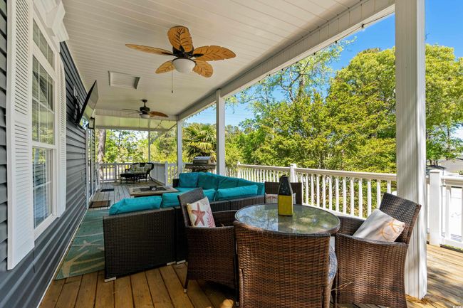 Wooden deck featuring area for grilling, a ceiling fan, and an outdoor hangout area | Image 12