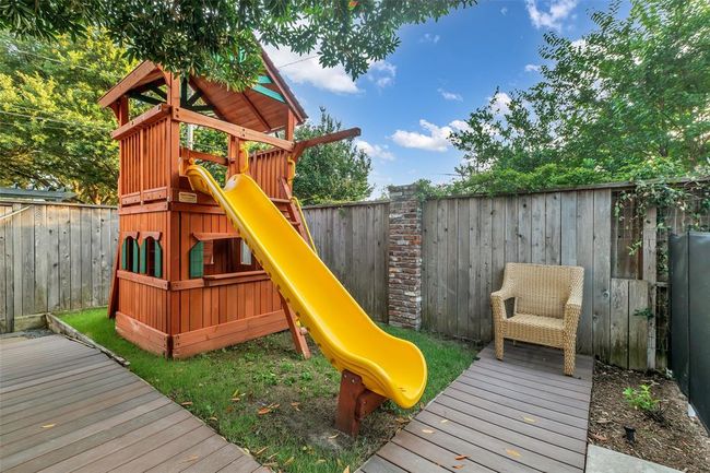 The backyard offers a delightful wooden playhouse with a slide, ideal for family fun and outdoor enjoyment. | Image 27