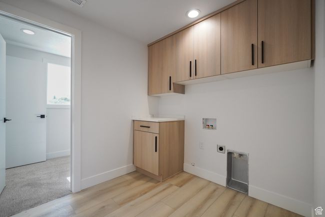 Washroom featuring electric dryer hookup, hookup for a washing machine, cabinet space, light wood-style flooring, and recessed lighting | Image 23