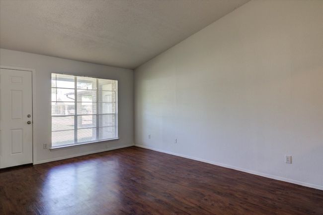 Spare room with baseboards, a textured ceiling, vaulted ceiling, and dark wood-style floors | Image 7