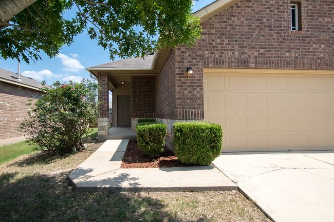 Entrance to property featuring brick siding, concrete driveway, and an attached garage | Image 15